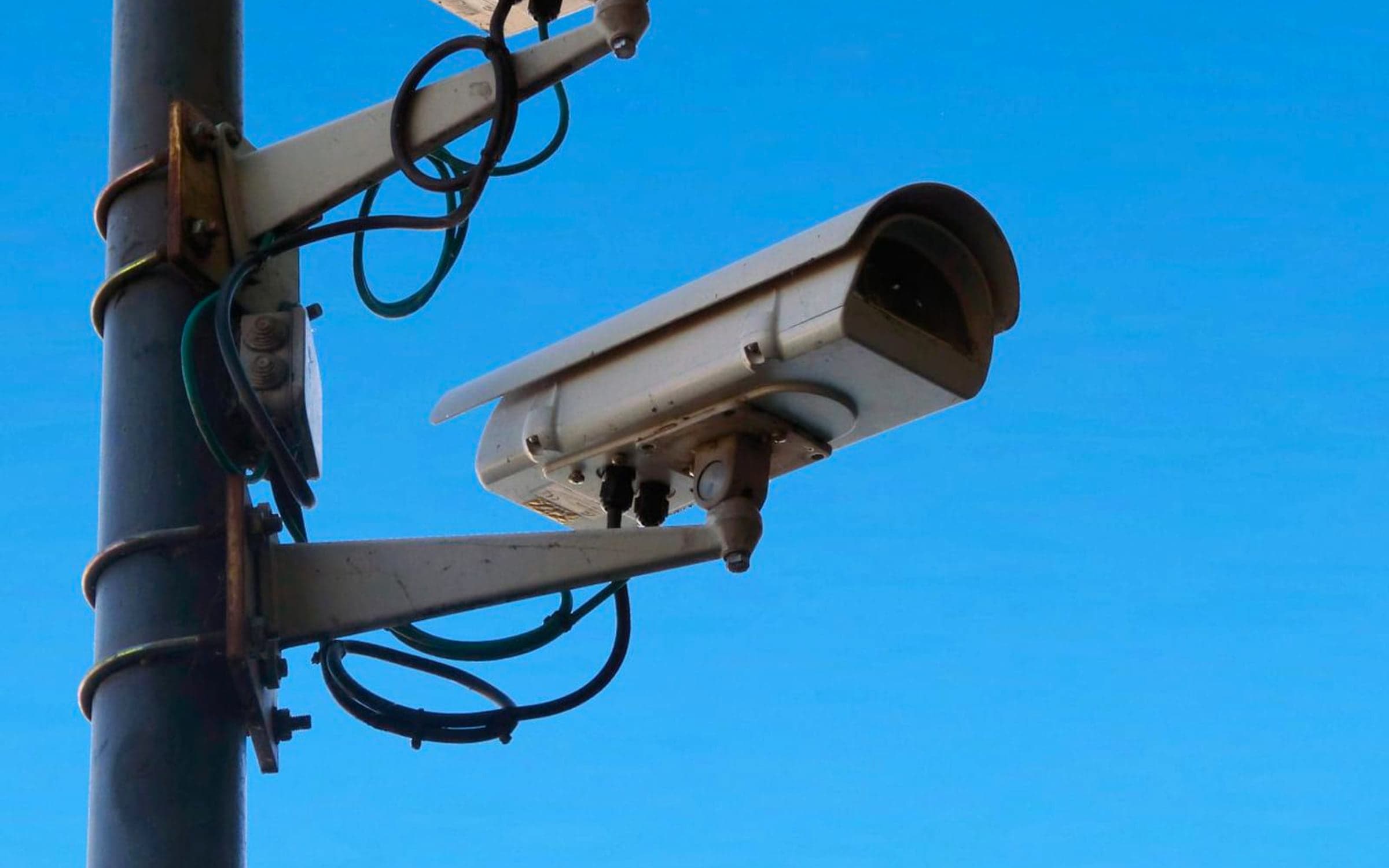 Two CCTV cameras on a pole against a clear blue sky