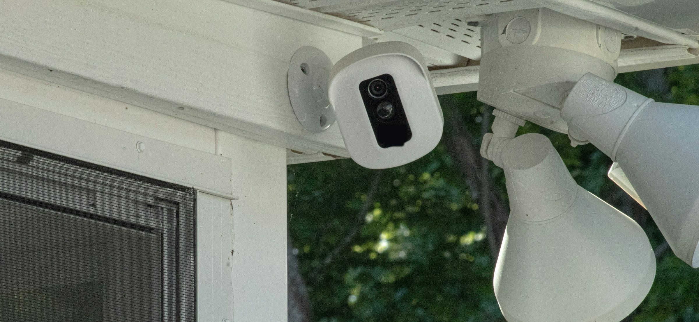 Wireless security camera and floodlights mounted under the eaves of a house